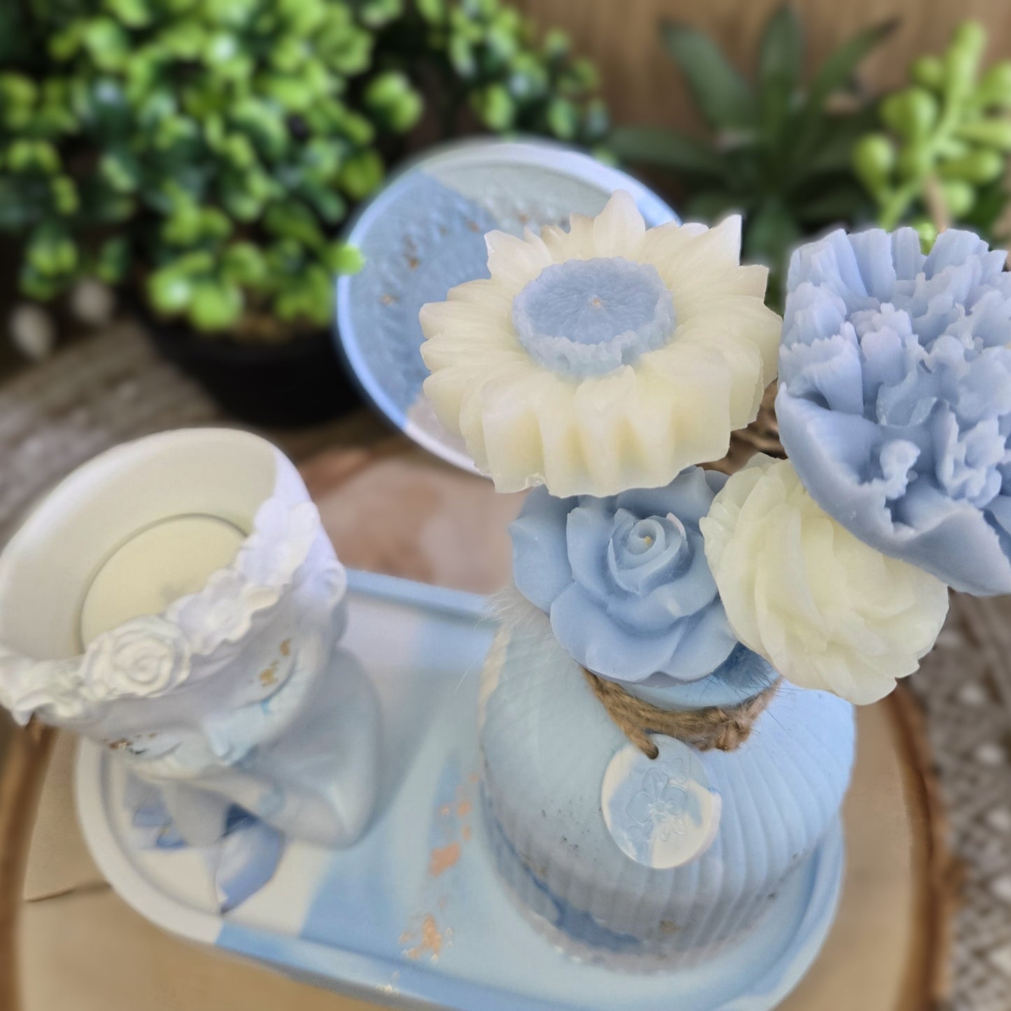 Gros plan sur les fleurs en cire coco bleu pastel et blanc prêtes à parfumer la pièce.
