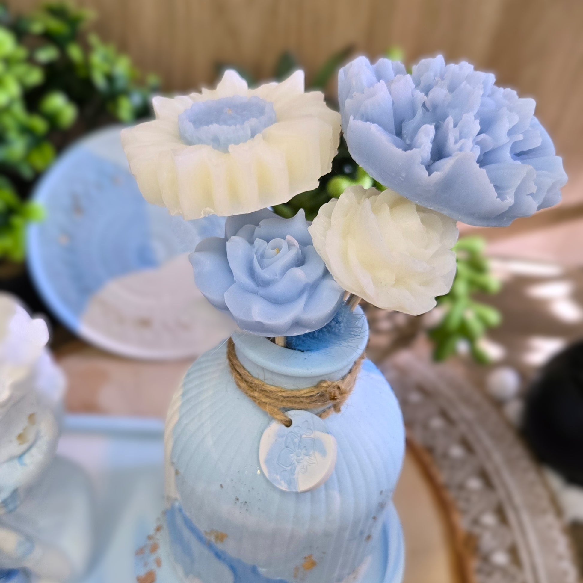 Gros plan sur les fleurs en cire coco bleu pastel et blanc prêtes à parfumer la pièce.

