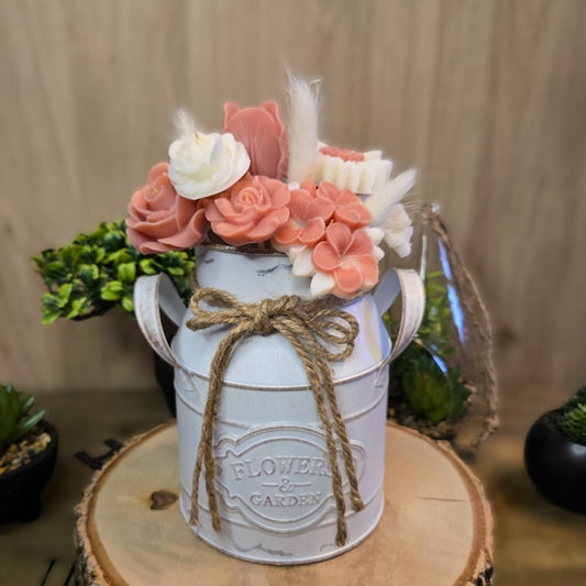 Bouquet parfumé en cire coco tons rose et blanc dans un vase vintage blanc, décor champêtre sur rondin de bois.


